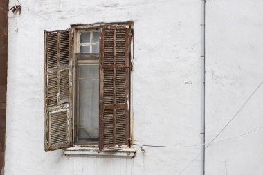 Eski ahşap kepenkler beyaz yıpranmış taş bir duvarın camında