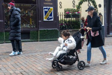 Londra, İngiltere, 12 Aralık 2025, Londra 'daki tarihi Gordon' s Wine Bar 'ın önünden bebek arabasıyla geçen bir kadın.