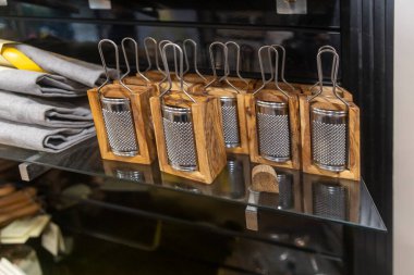 Mutfak gereçleri dükkanındaki cam bir rafta duran paslanmaz çelik ağlarla küçük zeytin rendeleyiciler.