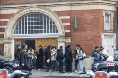 Londra, İngiltere, 12 Aralık 2026, Öğrenciler bir binanın önünde UCL sınavı tabelasıyla duruyorlar.