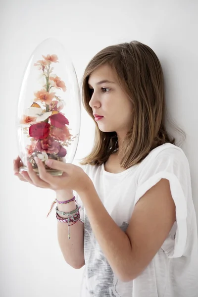 Tiener is een glazen pot met bloemen en vlinders kijken — Stockfoto