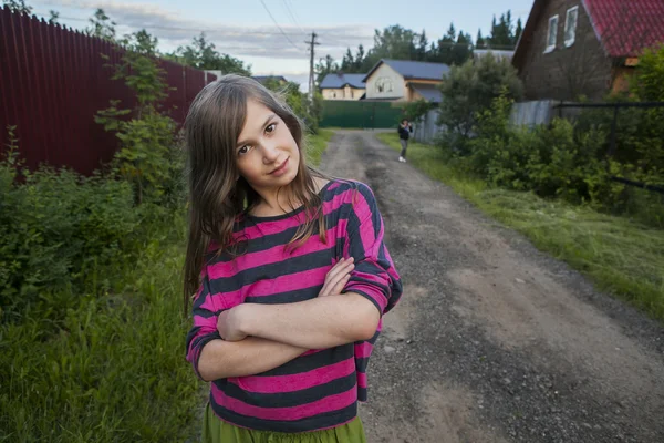 Улыбающаяся девочка-подросток в красной полосатой рубашке, стоящая на стреме — стоковое фото