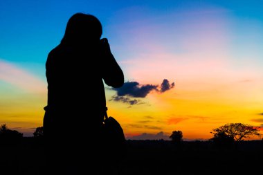 Gün batımı geçmişi olan siluet fotoğrafçı.