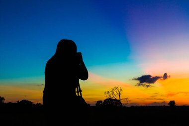 Gün batımı geçmişi olan siluet fotoğrafçı.