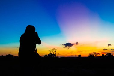 Gün batımı geçmişi olan siluet fotoğrafçı.