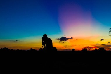 Gün batımı geçmişi olan siluet fotoğrafçı.
