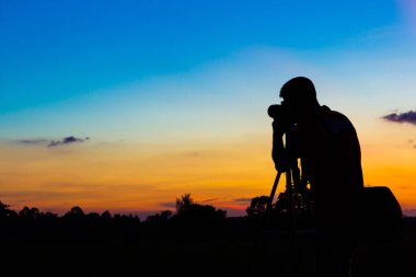 Gün batımı geçmişi olan siluet fotoğrafçı.