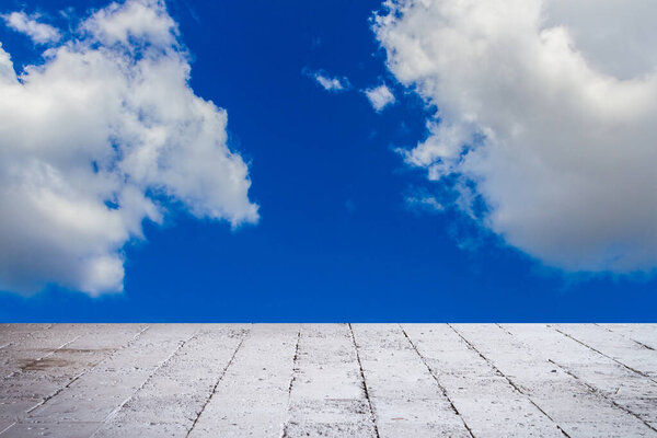 Blue sky with clouds and sun with cement floor background