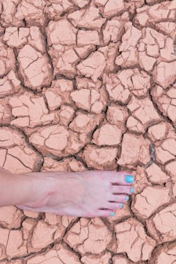 Nake wooman foot walk on walk on cracked earth background