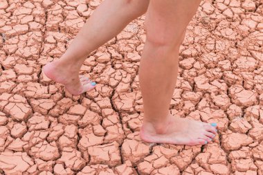 Nake wooman foot walk on walk on cracked earth background