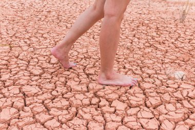 Nake wooman foot walk on walk on cracked earth background