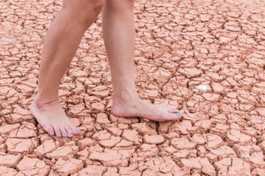 Nake wooman foot walk on walk on cracked earth background
