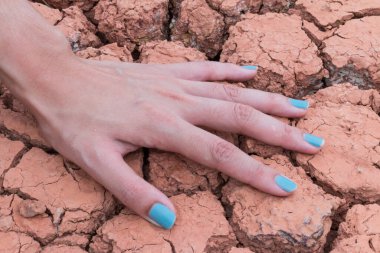 Kadın elleri kuru toprakta ya da çatlak toprak arka planda