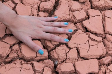 Kadın elleri kuru toprakta ya da çatlak toprak arka planda