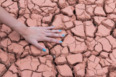 Kadın elleri kuru toprakta ya da çatlak toprak arka planda