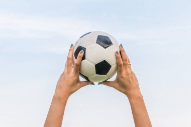 Eller futbol topunu tutuyor / gökyüzü mavi arka planda futbol oynuyor