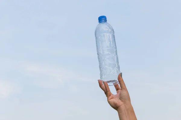 在蓝天的背景下 女人的手拿着一瓶饮用水 — 图库照片