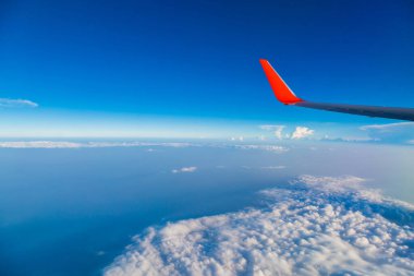 Pencereden bulutlu ve mavimsi uçağın kırmızı kanadı