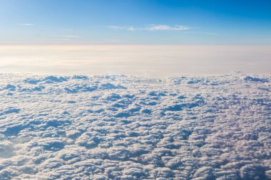 Kabarık bulutlar uçaktan siyah zemine bakıyor.