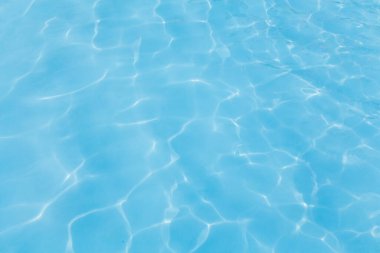 Havuz mavi suyu güneşe yansıyor.