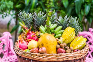 Yeşil arka planda sepette çok çeşitli egzotik meyveler var.