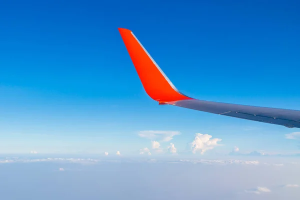 Red Wing of airplane with cloud and bluesky from window