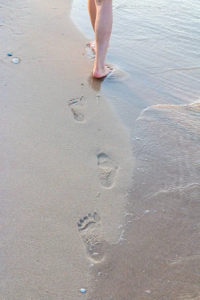 寂寞的女孩在沙滩上走着 她的脚印波涛汹涌 — 图库照片