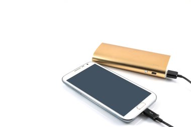 Altın güç bankası beyaz arkaplanda beyaz akıllı telefonu şarj ediyor