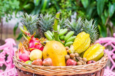Yeşil arka planda sepette çok çeşitli egzotik meyveler var.