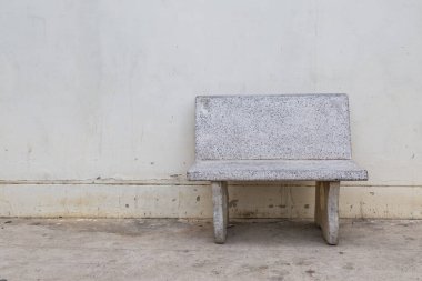 Beton duvardaki boş, eski taş sandalye.