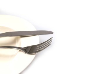 Beyaz arka planda izole edilmiş beyaz bir tabakta paslanmaz çelik çatal ve bıçak.