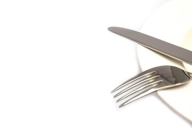 Beyaz arka planda izole edilmiş beyaz bir tabakta paslanmaz çelik çatal ve bıçak.