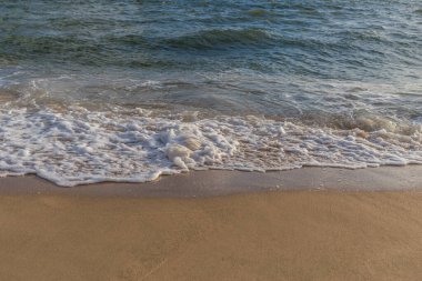 Güneşli bir günde kumlu sahilde denizin dalgası