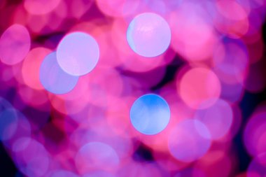 Kırmızı, pembe, beyaz, sarı ve turkuaz Noel ışıkları arka planda.