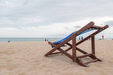 Kumsalda deniz ve gökyüzü arka planında bir sahil sandalyesi