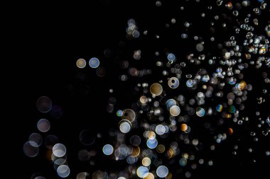 Su damlaları havada süzülüyor. Işıkla yansıtılıyor.