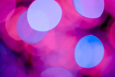 Kırmızı, pembe, beyaz, sarı ve turkuaz Noel ışıkları arka planda.