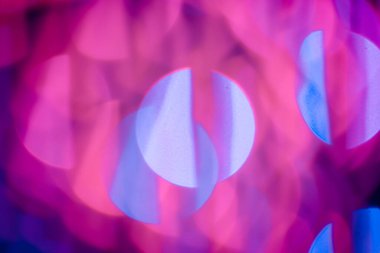 Kırmızı, pembe, beyaz, sarı ve turkuaz Noel ışıkları arka planda.