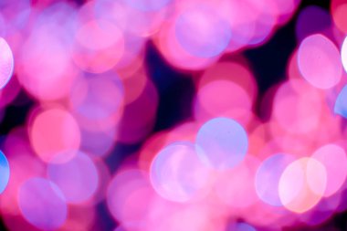 Kırmızı, pembe, beyaz, sarı ve turkuaz Noel ışıkları arka planda.