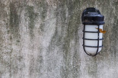 Gri beton duvar arka planındaki klasik lamba.