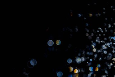 Su damlaları havada süzülüyor. Işıkla yansıtılıyor.