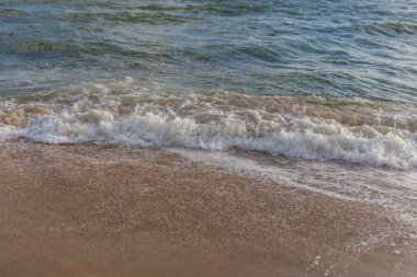 Güneşli bir günde kumlu sahilde denizin dalgası