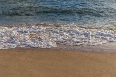 Güneşli bir günde kumlu sahilde denizin dalgası