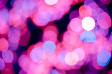 Kırmızı, pembe, beyaz, sarı ve turkuaz Noel ışıkları arka planda.