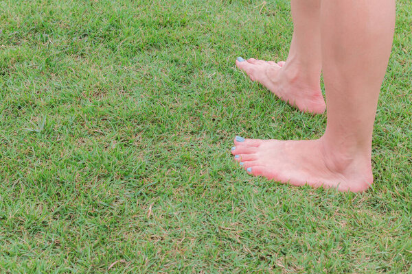 nake barefoot step on the green grass background