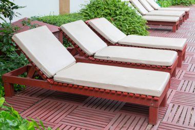 Havuz kenarındaki havuz sandalyelerinde ağaç var.