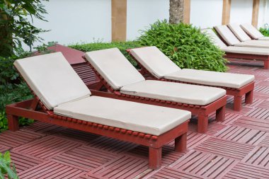 Havuz kenarındaki havuz sandalyelerinde ağaç var.