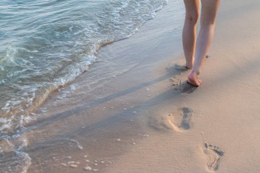 Sahil yolculuğu yalnız - kumsalda tek başına yürüyen kadın kumsalda ayak izleri bırakıyor kadın ayaklarının yakın plan detayları ve altın kum arka plan