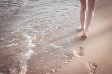 Sahil yolculuğu yalnız - kumsalda tek başına yürüyen kadın kumsalda ayak izleri bırakıyor kadın ayaklarının yakın plan detayları ve altın kum arka plan