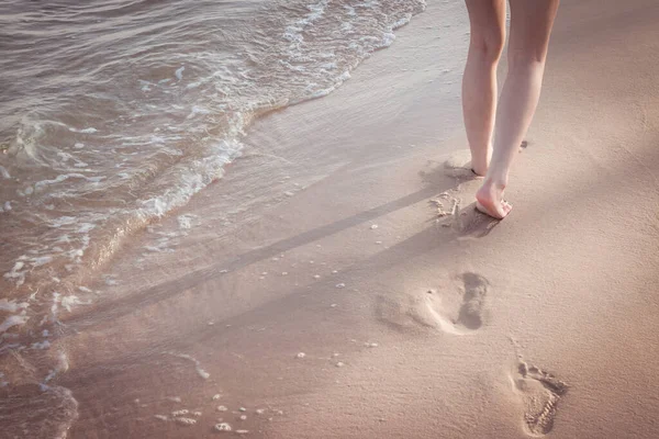 海滩旅行 一个女人独自走在沙滩上 在沙滩上留下脚印 女足和金黄色背景的服装细节 — 图库照片